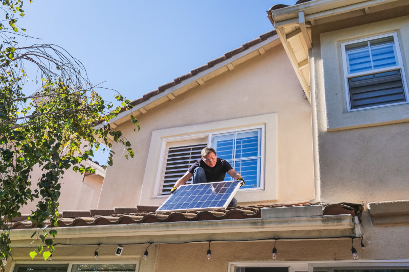 Ein Mann montiert ein Solarpanel auf seinem Wohnhaus